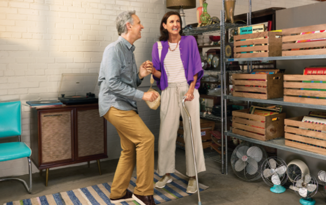 A couple is spontaneously dancing together in a thrift store.